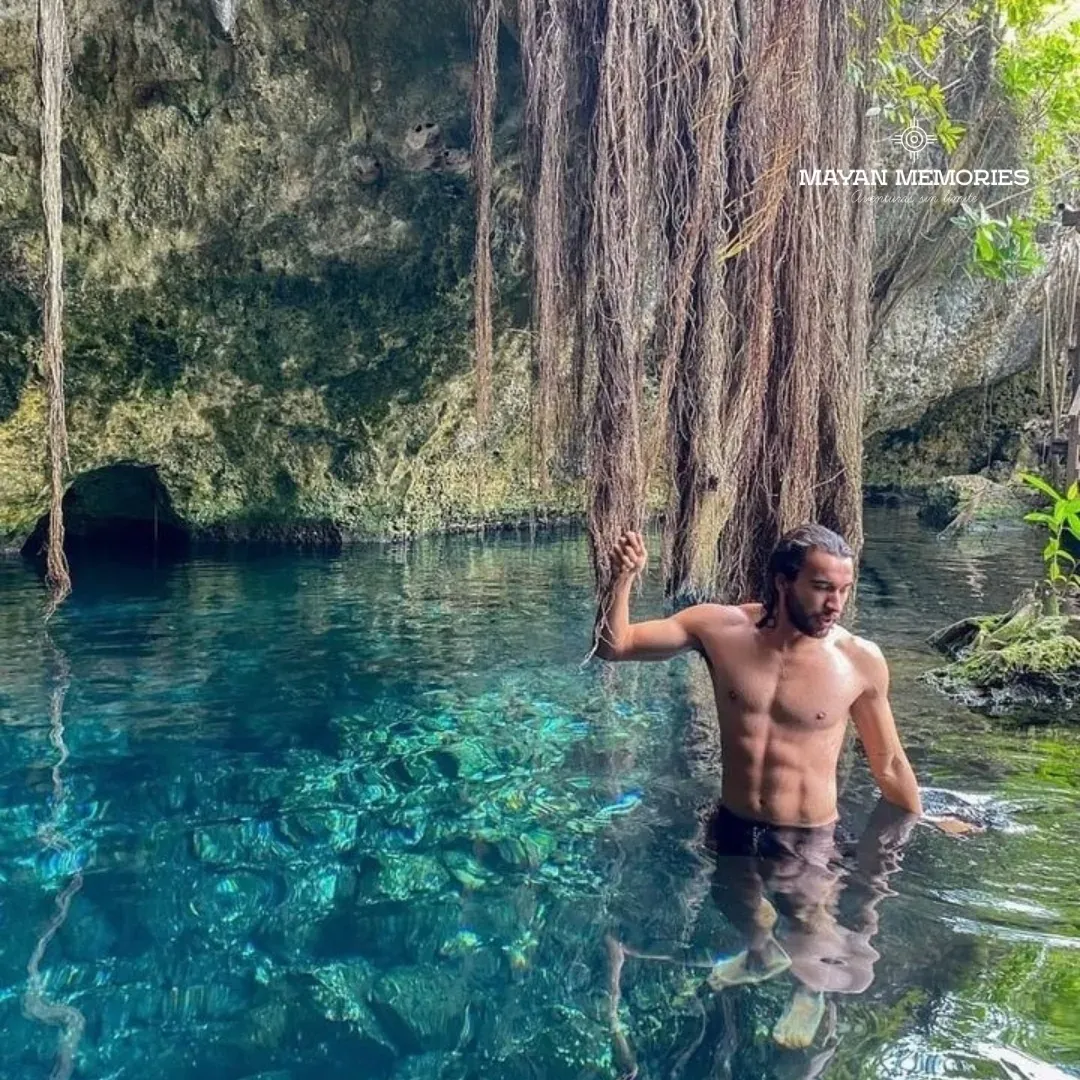 Man standing in the water of a cenote with hanging roots