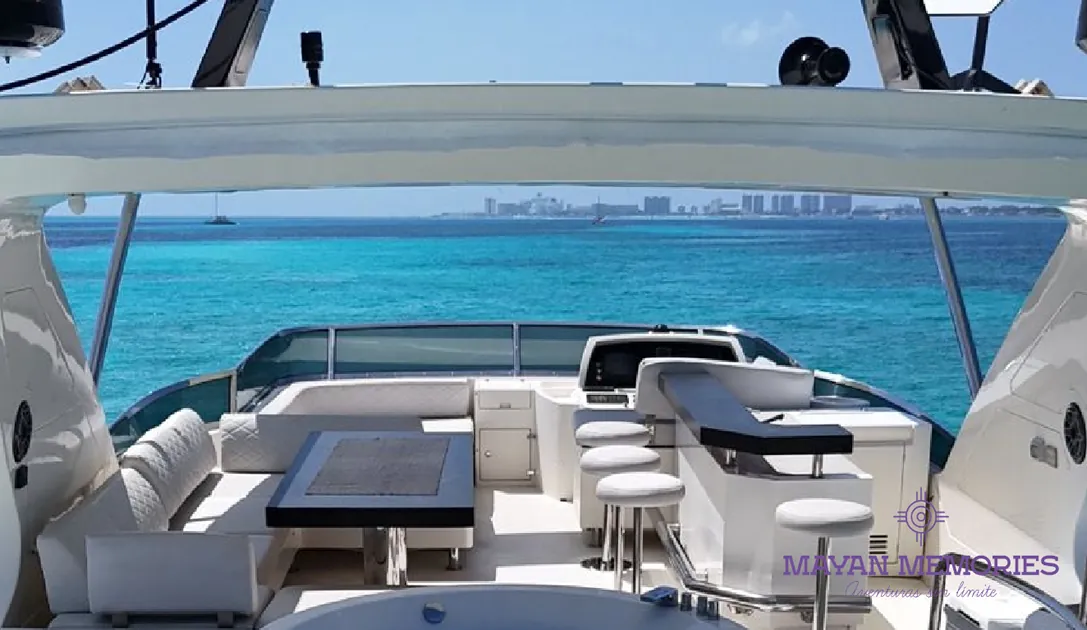 Yacht flybridge with bar and seating, buildings on the coast behind