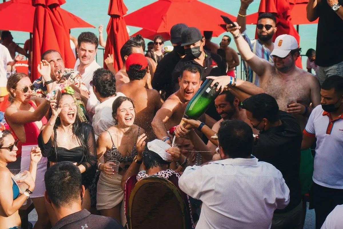 Multitud bailando bajo sombrillas rojas en el club de playa