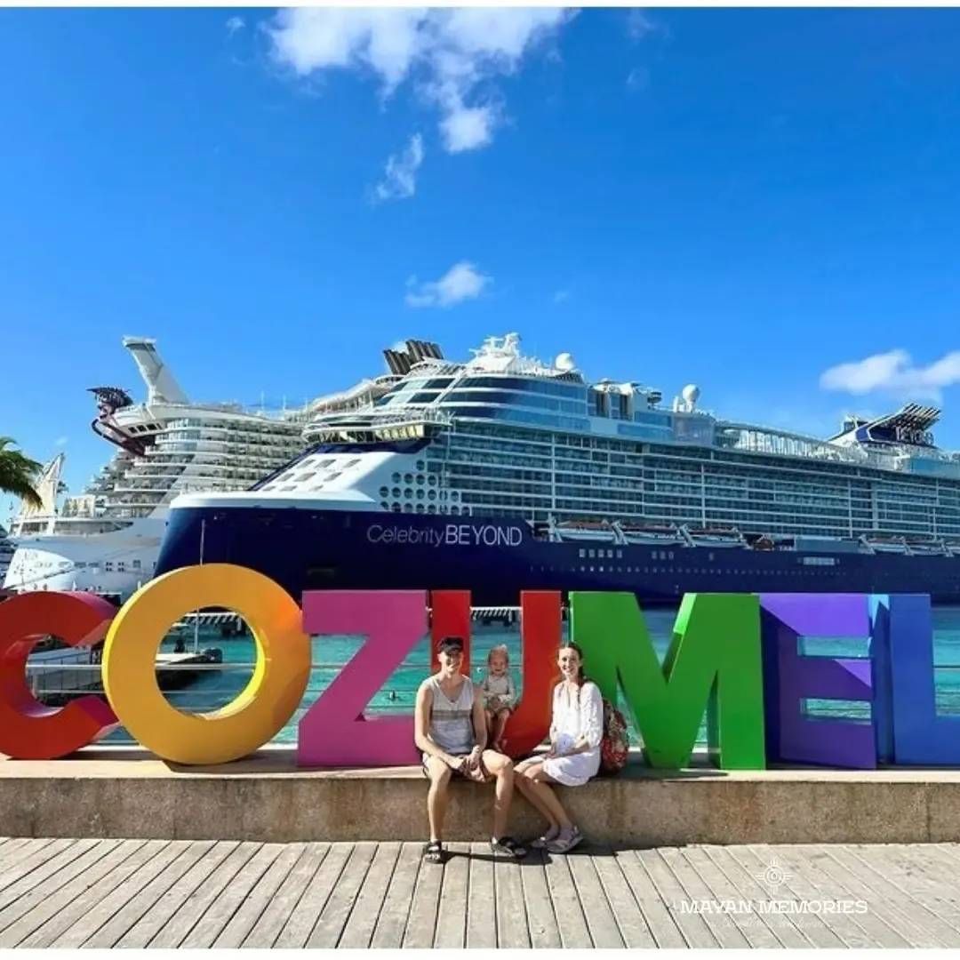 Couple in front of the Cozumel letters with a cruise ship behind