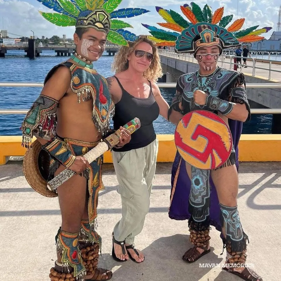 Visitor posing with two performers dressed as Mayan warriors