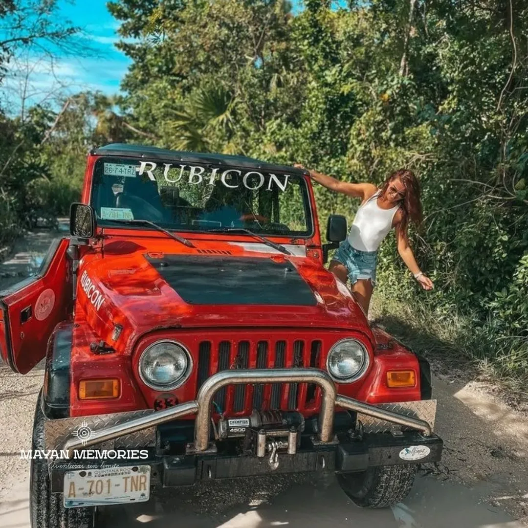 Mujer junto a un jeep rojo entre la selva