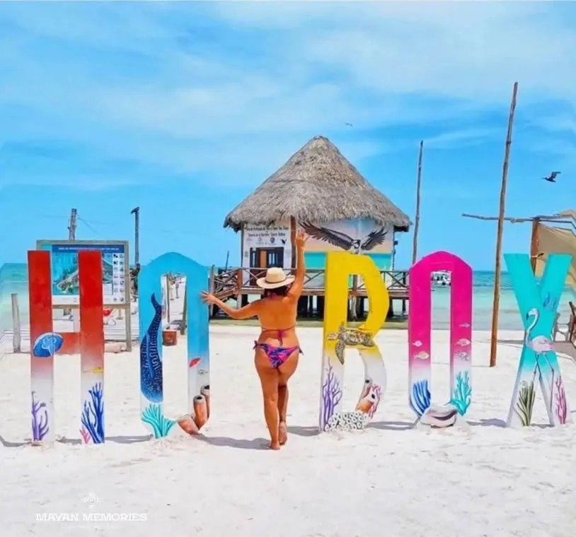 Woman in front of the colorful Holbox letters with a palapa behind
