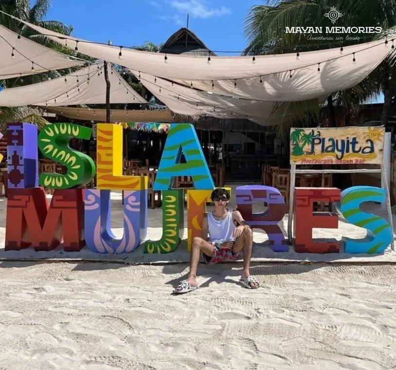 Man sitting in front of the colorful Isla Mujeres letters