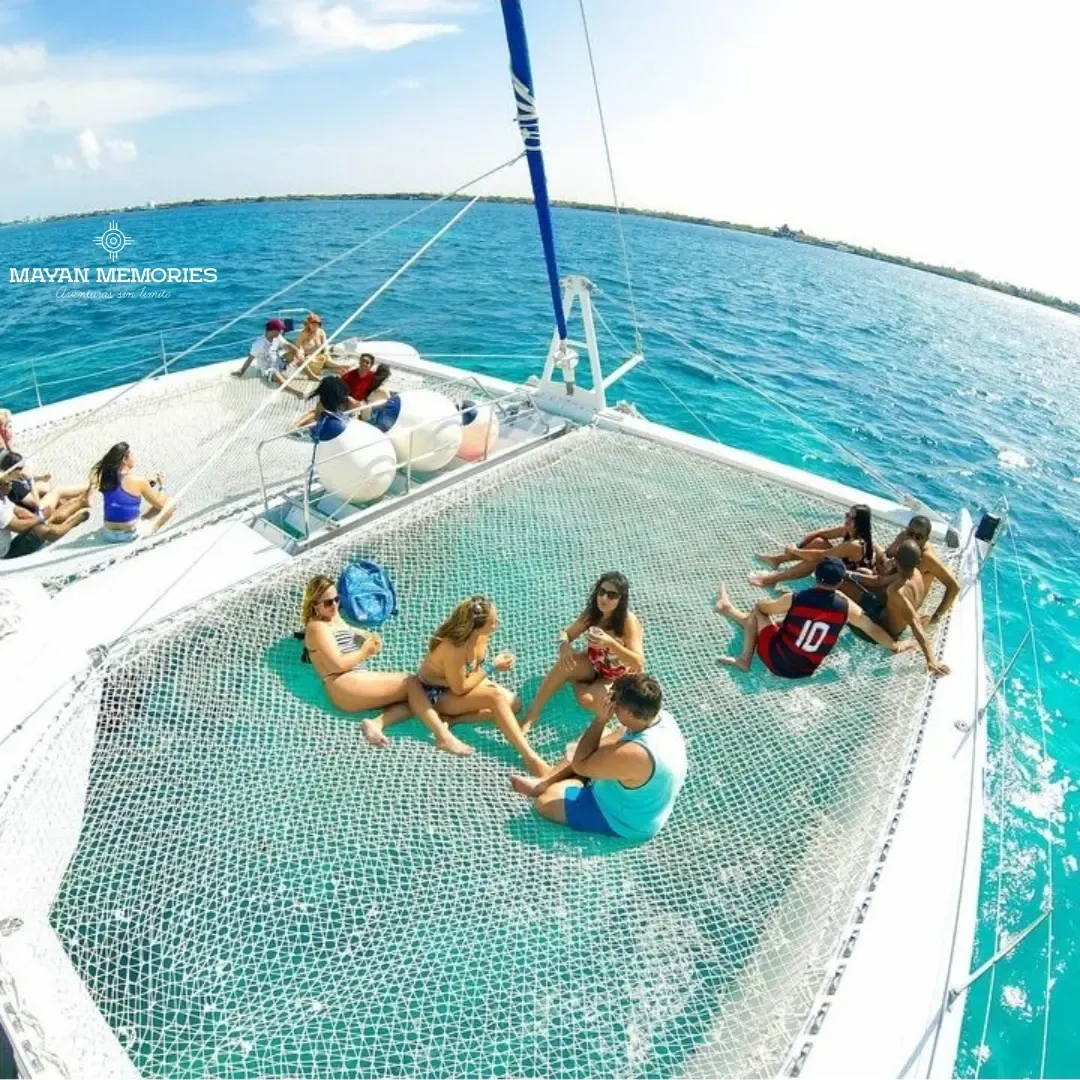 Personas descansando en la red del catamarán sobre el agua turquesa
