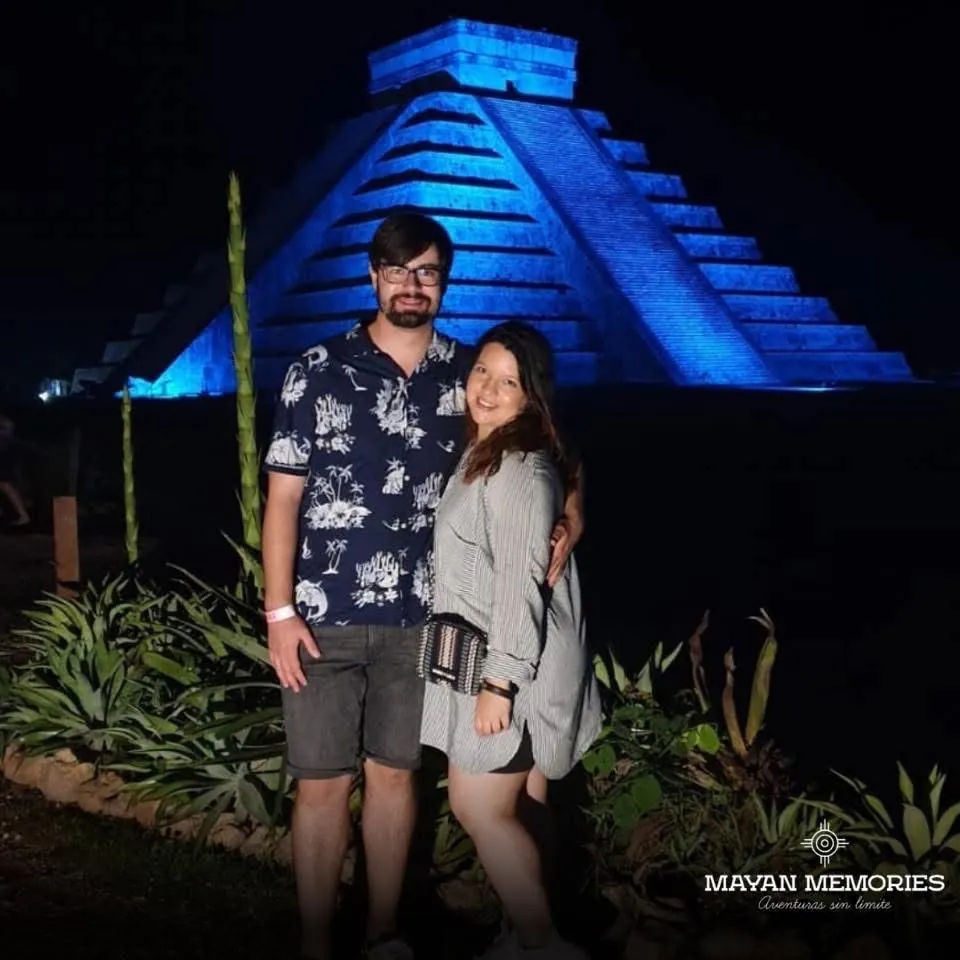 Pareja frente a la pirámide iluminada de azul de noche