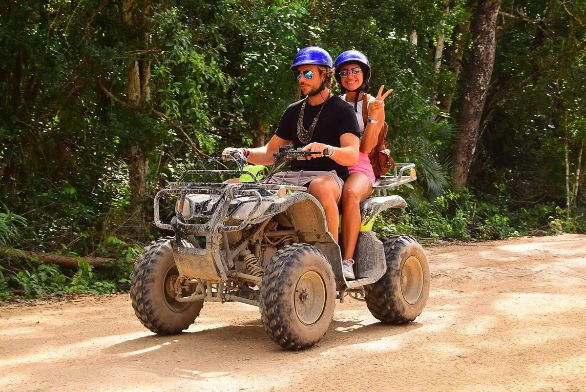 Couple riding an ATV along a dirt road