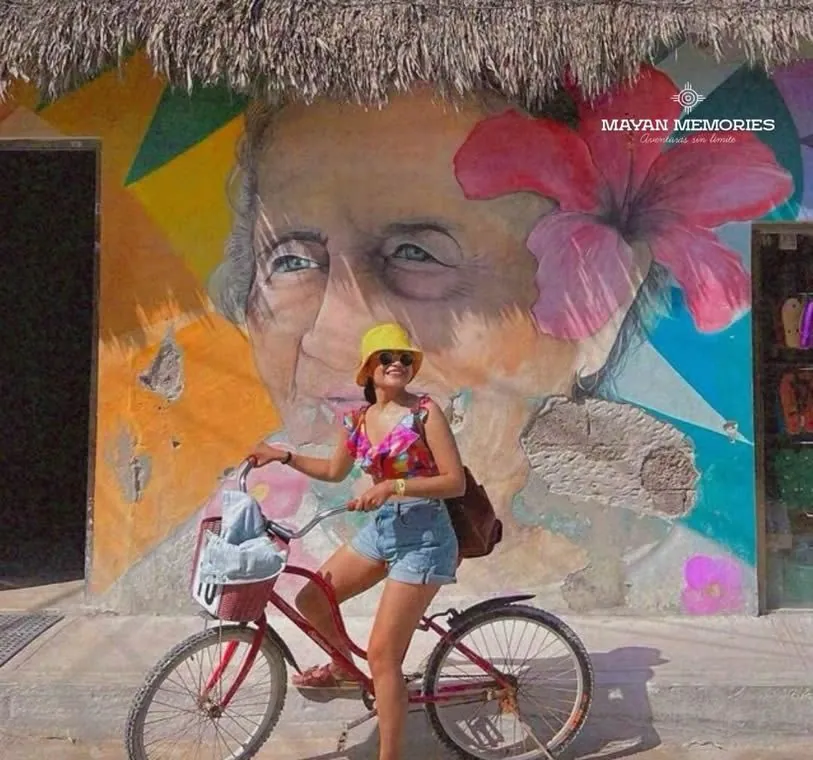 Woman on a bicycle in front of a colorful mural in Holbox