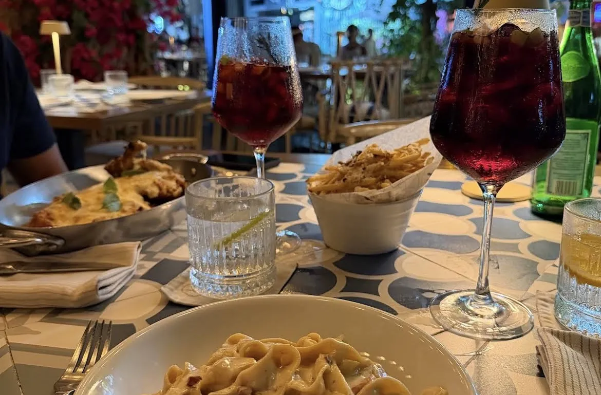 Glasses of red wine with pasta and fries on the table