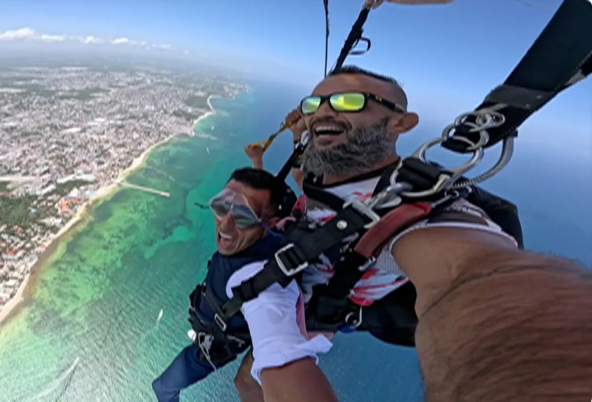Tandem skydivers in freefall above the coast