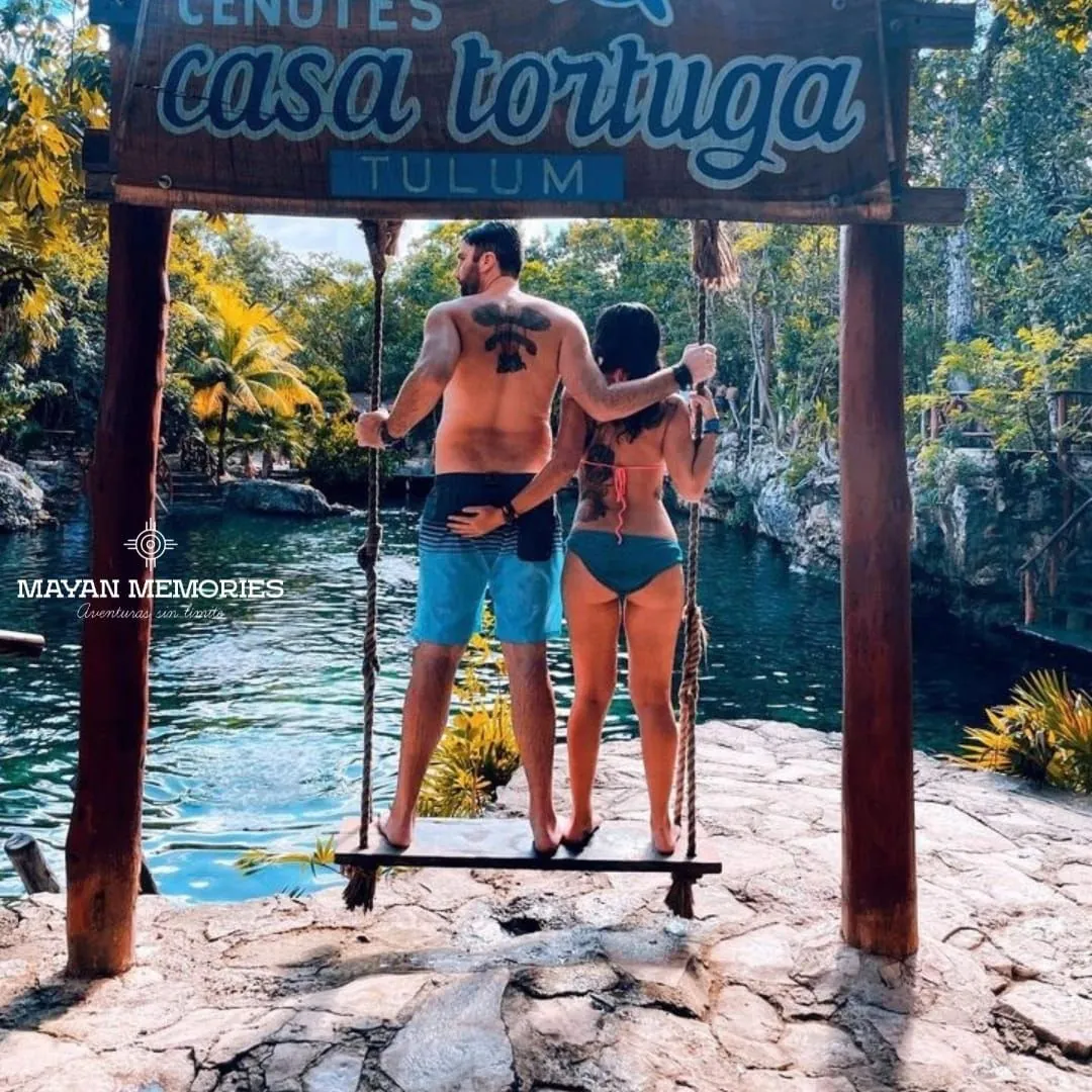 Pareja en un columpio de madera sobre un cenote