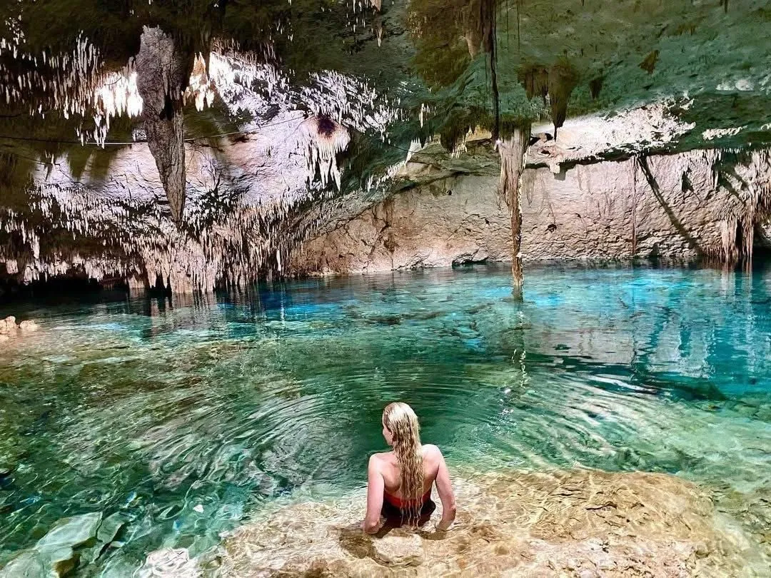 Mujer nadando en el agua cristalina de un cenote de caverna
